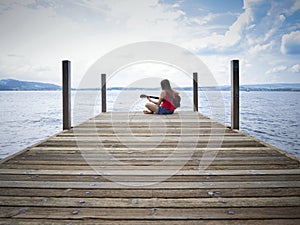 Woman playing guitar by the lake