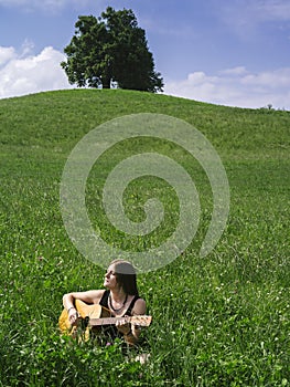 Woman playing guitar in large field