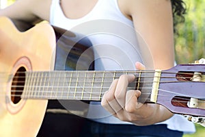 Woman playing guitar at the park.