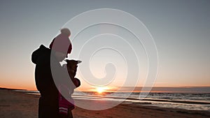 Woman playing with her dog at sunset near baltic sea