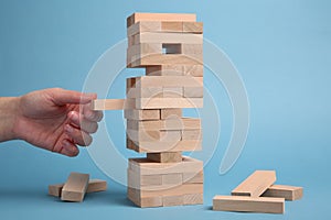 Woman playing Jenga on light blue background, closeup