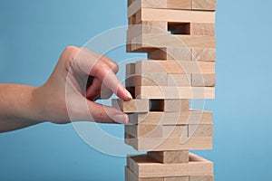 Woman playing Jenga on light blue background, closeup