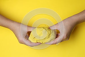 Woman playing with kinetic sand on yellow background, top view