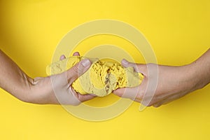 Woman playing with kinetic sand on yellow background, top view