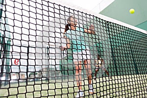 Woman playing paddle tennis, focus on net