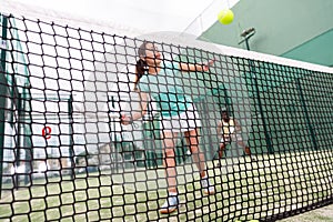 Woman playing paddle tennis, focus on net