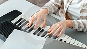 Woman playing piano record music on synthesizer using notes and laptop. Female hands musician pianist improves skills