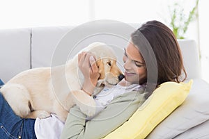 Woman playing with puppy while lying on sofa