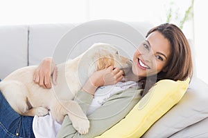 Woman playing with puppy on sofa