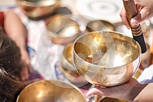 Woman playing a singing bowls also known as Tibetan Singing Bowls, Himalayan bowls. Making sound massage.