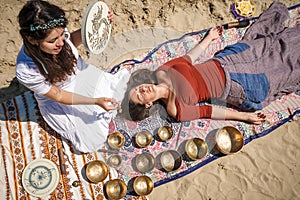 Woman playing a singing bowls also known as Tibetan Singing Bowls, Himalayan bowls. Making sound massage.