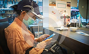 A woman playing with a smartphone while waiting for the food ordered in restaurant