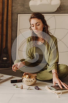 Woman playing on Tibetan singing bowl while sitting on yoga mat. Soft focus blurred and noise effect