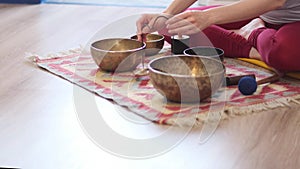 Woman playing on Tibetan singing bowl while sitting on yoga mat. Vintage tonned.