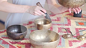 Woman playing on Tibetan singing bowl while sitting on yoga mat. Vintage tonned.