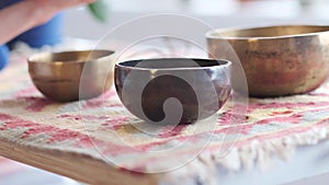 Woman playing on Tibetan singing bowl while sitting on yoga mat. Vintage tonned.