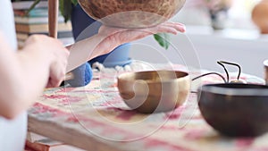 Woman playing on Tibetan singing bowl while sitting on yoga mat. Vintage tonned.