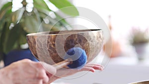 Woman playing on Tibetan singing bowl while sitting on yoga mat. Vintage tonned.