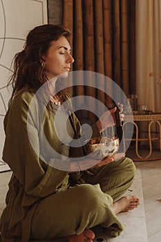 Woman playing on Tibetan singing bowl while sitting on yoga mat. Vintage tonned. Soft focus blurred and noise effect