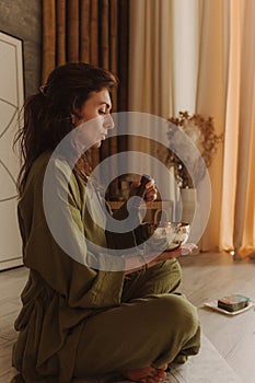 Woman playing on Tibetan singing bowl while sitting on yoga mat. Vintage tonned. Soft focus and noise effect