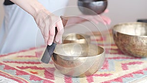 Woman playing on Tibetan singing bowl while sitting on yoga mat. Vintage tonned. stock footage. Slow Motion video. Close