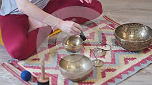 Woman playing on Tibetan singing bowl while sitting on yoga mat. Vintage tonned. stock footage. Slow Motion video. Close