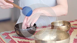 Woman playing on Tibetan singing bowl while sitting on yoga mat. Vintage tonned. stock footage. Slow Motion video. Close