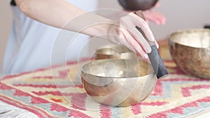 Woman playing on Tibetan singing bowl while sitting on yoga mat. Vintage tonned. stock footage. Slow Motion video. Close