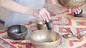 Woman playing on Tibetan singing bowl while sitting on yoga mat. Vintage tonned. stock footage. Slow Motion video. Close