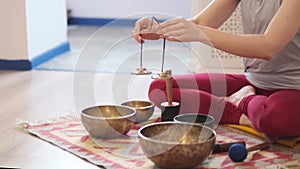 Woman playing on Tibetan singing bowl while sitting on yoga mat. Vintage tonned. stock footage. Slow Motion video. Close