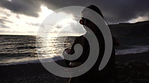 Woman playing on Tibetan singing bowl at Sunset on Beach. Close-up of woman hands playing on small Tibetan Singing Bowl