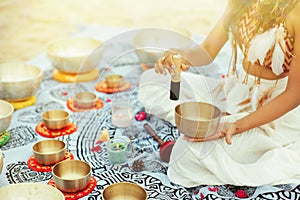 Woman playing Tibetan Singing Bowls with Mallet on Beach. Relaxing Meditative Music Therapy and Sound Healing Massage. Spiritual