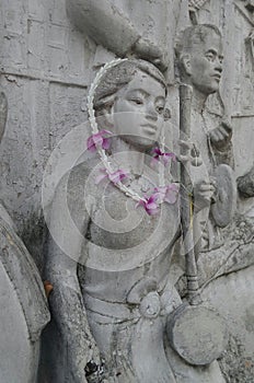 Woman playing treblefiddle sculpture and fresh garland