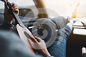 A woman playing Ukulele in the car