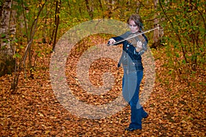 Woman playing violin in autumn park