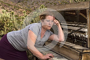 Woman Playing Wooden Piano in Desert, Contemplative Expression