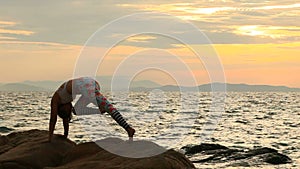 Woman playing yoga pose on sea beach