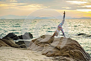 woman playing yoga pose on sea beach against beautiful sun rising sky