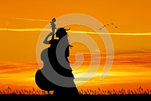 Woman plays the cello at sunset