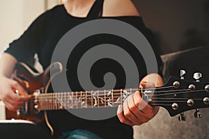 Woman plays chord on electric hollowbody guitar with richly ornamented ftretboard.