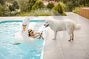 Woman plays with a dog while swimming at pool