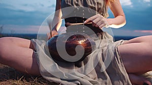 Woman plays drumsticks on a steel-tongued drum in the great outdoors.