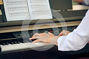 Woman plays electric piano at outdoor music performance, close up view to nimble hands