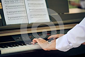 Woman plays electric piano at outdoor music performance, close up view to nimble hands