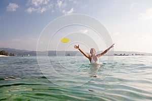 Woman plays frisbee in the water of beautiful ocean