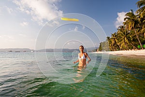 Woman plays frisbee in the water of beautiful ocean