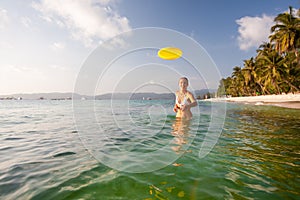 Woman plays frisbee in the water of beautiful ocean
