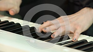 Woman plays by hands on white digital piano, close-up shooting with defocus. Girl is playing by fingers on keyboard or
