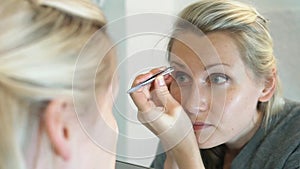 Woman plucking eyebrows with tweezers