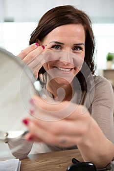 woman plucks eyebrows and smiles at camera